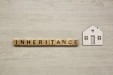 Kelime kalıtımsal küp ve ev modeli hafif ahşap arka planda, düz yatar