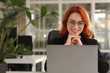 Ofiste dizüstü bilgisayarla çalışan mutlu kadın