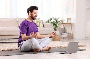 Evde dizüstü bilgisayarın yanında meditasyon yapan bir adam, mesaj için alan