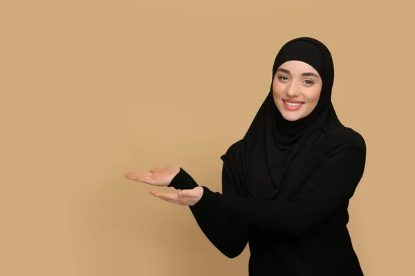 Мусульманська Жінка Хіджабі Вказує Щось Бежевому Тлі — стокове фото