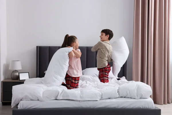 Brother and sister having pillow fight while changing bed linens in bedroom