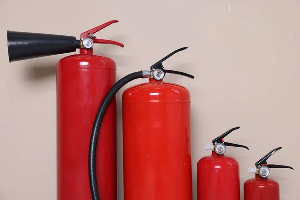 Set of fire extinguishers on beige background