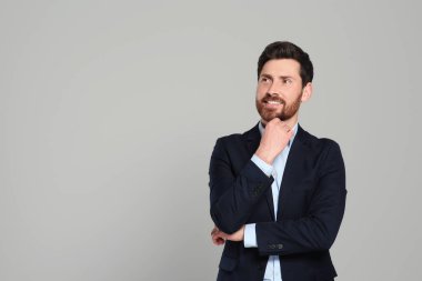 Gri arka planda güzel takım elbiseli yakışıklı bir emlakçı. Mesaj için yer var.