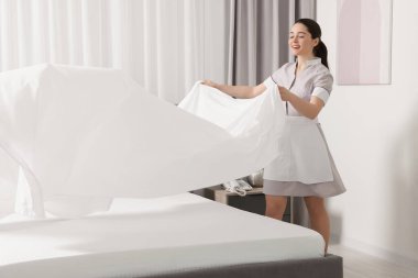 Genç hizmetçi otel odasında yatak yapma