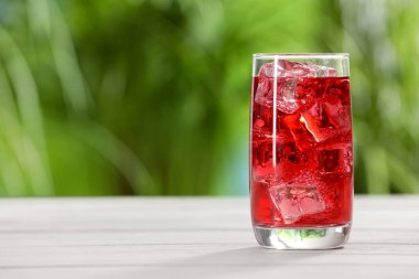 Bir bardak ferahlatıcı soda, beyaz masada buz küpleri, yazı için yer.