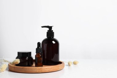 Farklı kozmetik ürünleri ve beyaz ahşap masadaki kuru çiviler. Metin için boşluk