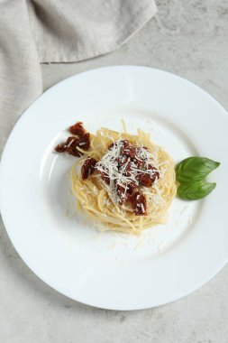 Kurutulmuş domatesli ve beyaz masadaki parmesan peynirli leziz spagetti. Makarna yemeğinin enfes sunumu