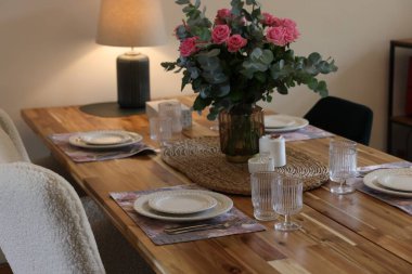 İçeride mum ve buket bulunan güzel bir masa. Vazoda gül ve okaliptüs dalları