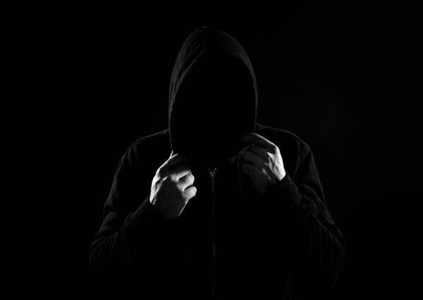 Anonymous man in hood on black background