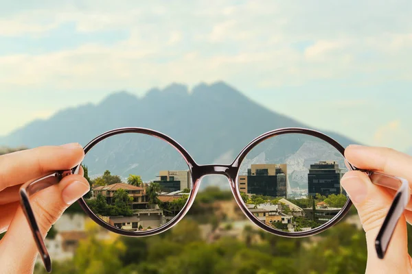 Vision correction. Woman looking through glasses and seeing landscape clearer