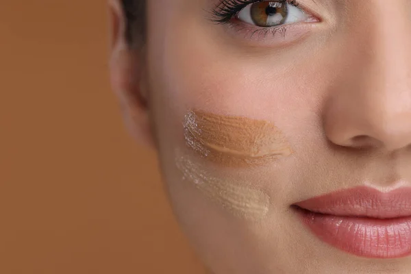 stock image Woman with swatches of foundation on face against brown background, closeup