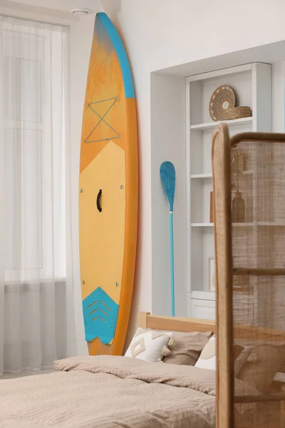 SUP board, bed and furniture in room. Interior design