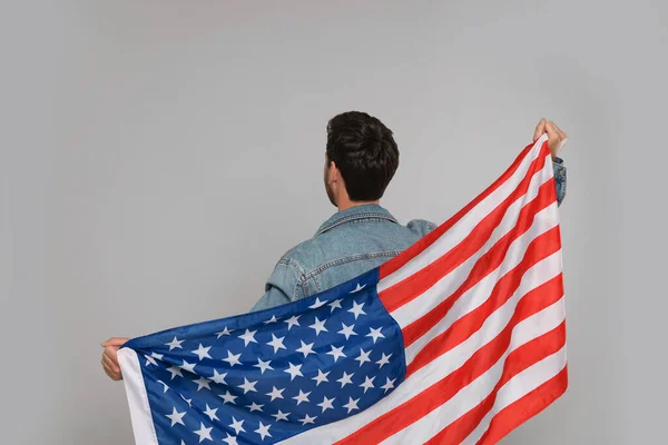 7月4日 アメリカ独立記念日 灰色の背景にアメリカの旗を持つ男 バックビュー — ストック写真