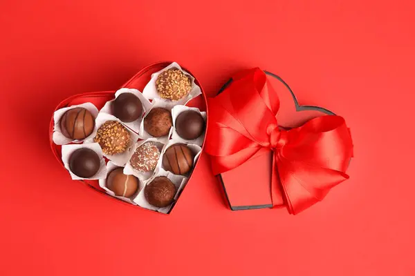 红桌上有香甜巧克力糖果的心形盒 — 图库照片