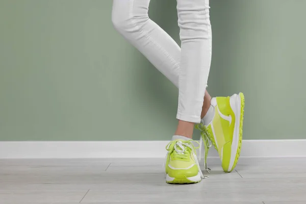 Kvinna Bär Par Nya Snygga Sneakers Nära Ljusgrön Vägg Närbild — Stockfoto