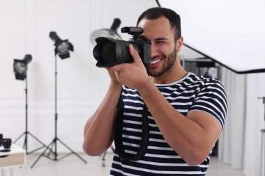 Modern fotoğraf stüdyosunda fotoğraf çeken genç profesyonel fotoğrafçı.