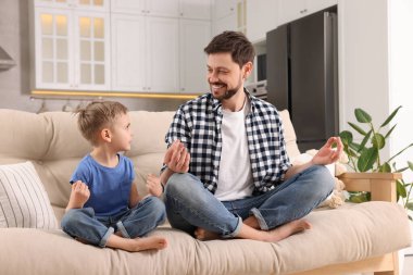 Baba oğul evdeki kanepede birlikte meditasyon yapıyorlar. Ahenk ve zen