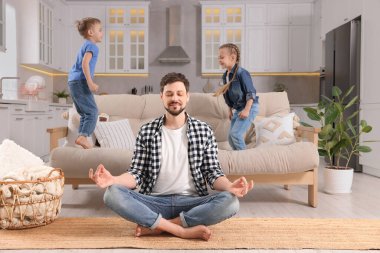 Baba, çocuklar evde oynarken meditasyon yapıyor.