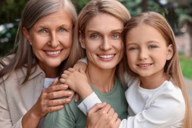 Three generations. Happy grandmother, her daughter and granddaughter outdoors