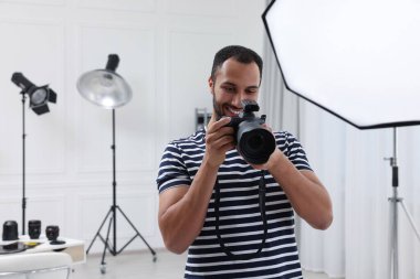 Modern fotoğraf stüdyosunda kamerası olan genç profesyonel fotoğrafçı.