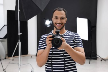 Modern fotoğraf stüdyosunda kamerası olan genç profesyonel fotoğrafçı.
