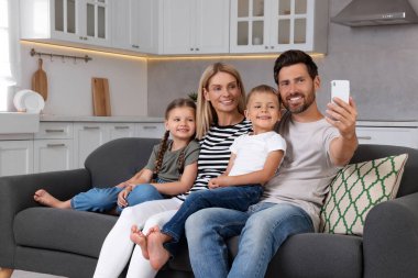 Mutlu bir aile evdeki kanepede selfie çekiyor.