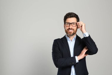 Gri arka planda güzel takım elbiseli yakışıklı bir emlakçı. Mesaj için yer var.
