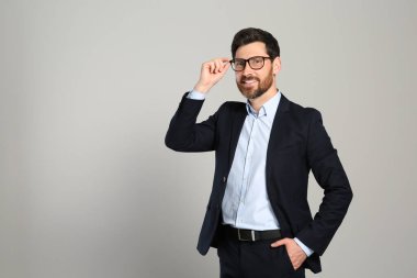 Gri arka planda güzel takım elbiseli yakışıklı bir emlakçı. Mesaj için yer var.