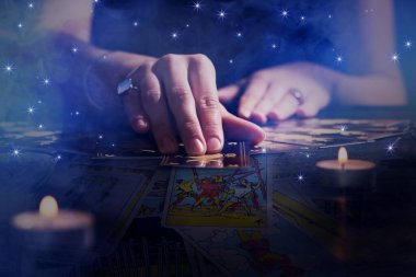 Kahin, karanlıkta tarot kartlarıyla geleceği öngörüyor, yakın plan. Çift pozlama