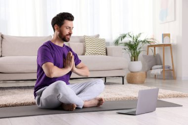 Evde dizüstü bilgisayarın yanında meditasyon yapan bir adam, mesaj için alan