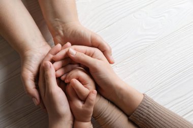 Aile, beyaz ahşap masada el ele tutuşuyor. Metin için boşluk