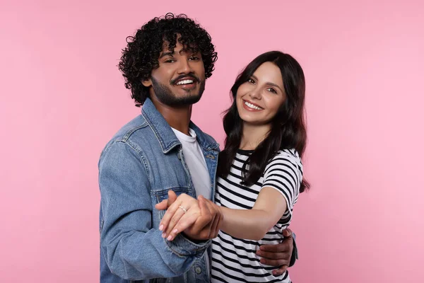 International dating. Happy couple dancing on pink background