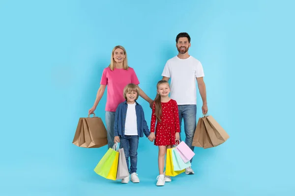 家庭购物 快乐的父母和孩子们 带着许多浅蓝色背景的彩包 — 图库照片