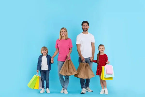 家庭购物 快乐的父母和孩子们 带着许多浅蓝色背景的彩包 — 图库照片