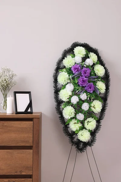 塑料花的花环和黑色缎带的框架 在房间里的冷藏箱上燃着蜡烛 丧葬属性 — 图库照片