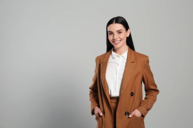 Gri arka planda güzel takım elbiseli güzel bir emlakçı. Mesaj için yer var.