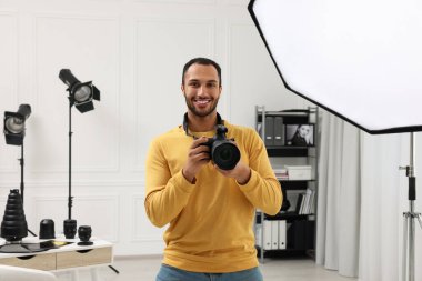 Modern fotoğraf stüdyosunda kamerası olan genç profesyonel fotoğrafçı.