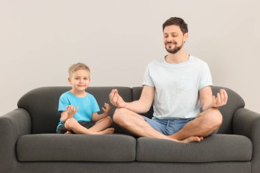 Baba oğul evdeki kanepede birlikte meditasyon yapıyorlar. Ahenk ve zen