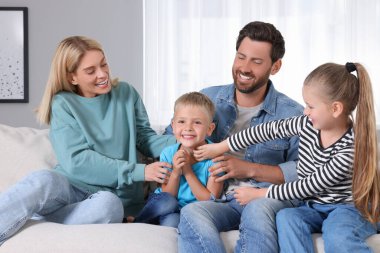 Mutlu aile evdeki kanepede birlikte eğleniyor.