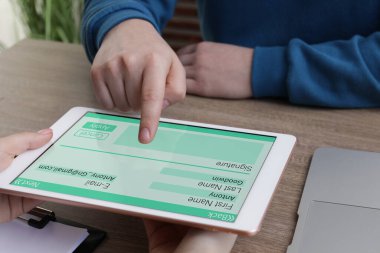 Elektronik imza. Ahşap masada tablet kullanan adam, yakın plan.