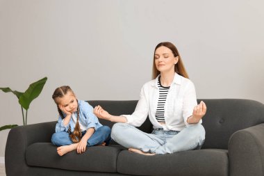 Anne, kızı evde sıkılırken meditasyon yapıyor.