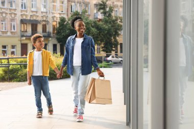 Family shopping. Happy mother and son with purchases near mall outdoors