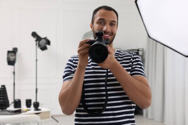 Modern fotoğraf stüdyosunda kamerası olan genç profesyonel fotoğrafçı.