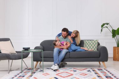 Mutlu aile evdeki kanepede birlikte eğleniyor.