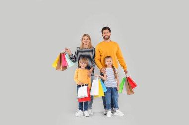 Aile alışverişi. Açık gri arka planda renkli çantaları olan mutlu ebeveynler ve çocuklar