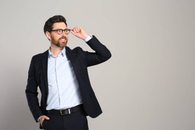 Gri arka planda güzel takım elbiseli yakışıklı bir emlakçı. Mesaj için yer var.