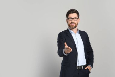 Gri arka planda güzel takım elbiseli yakışıklı bir emlakçı. Mesaj için yer var.