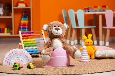 Pembe bebek lazımlığında oyuncak ayı ve odadaki diğer oyuncaklar. Tuvalet eğitimi