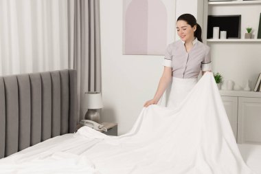 Genç hizmetçi otel odasında yatak yapma. Metin için yer