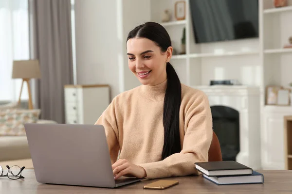 快乐的女人在房间的木制书桌边与笔记本电脑一起工作 — 图库照片